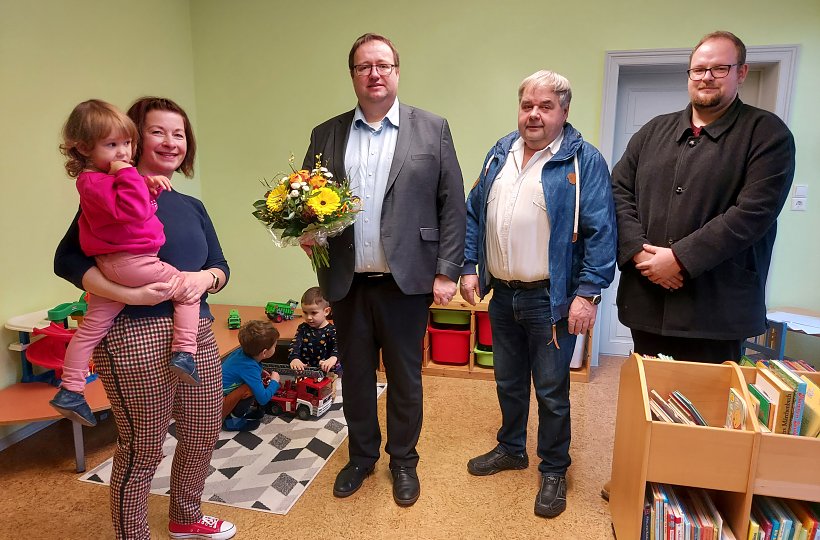 Wiedereröffnung der Kita in Göllnitz im Januar 2023, von links: Kita-Leiterin Kerstin Jungnickel mit Kind Maya, Amtsdirektor Marten Frontzek, Amtsausschussvorsitzender und Bürgermeister von Sallgast Frank Tischer und Ortsvorsteher von Göllnitz David Krüger. 
Foto: Sarah Große, ©Amt Kleine Elster